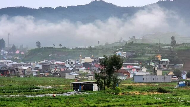 4K view of Flying through rain clouds above green mountain covered by jungle and small villages at Dieng, Central Java, Indoneisa. Wonderful rainy day. Natural landscape