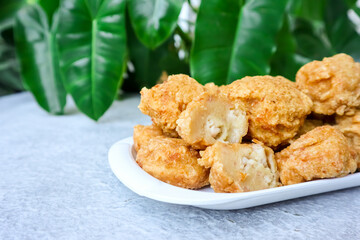 Bakso Goreng or Fried Chicken Ball, served with tomato or chili sauce on table with green foliage in the background