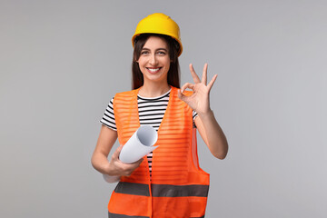 Architect in hard hat with draft showing ok gesture on light grey background