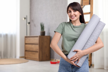 Young woman with wallpaper rolls at home