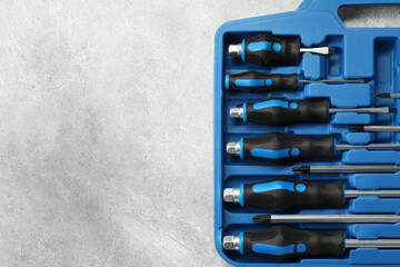 Set of screwdrivers in open toolbox on light grey textured table, top view. Space for text