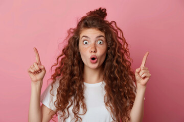 Fototapeta premium pretty woman with long curly hair being puzzled pointing up on pink background