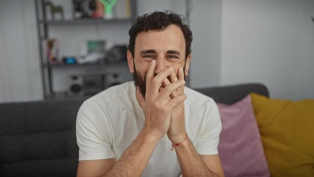 Cheerful middle age man embarrassed at home gossip, covering his smile with hand, laughing in a white t-shirt
