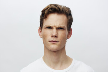 Young man with serious expression; confident male portrait; casual style white shirt