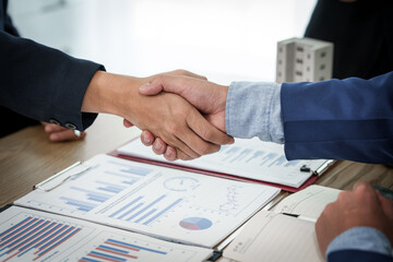 Two individuals shake hands in agreement after a successful business meeting with a condominium...