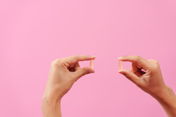 Gracefully, woman hand cradles a bottle of cod liver oil against a pink backdrop, representing health, nutrition, and the benefits of omega-3 supplementation. - obrazy, fototapety, plakaty