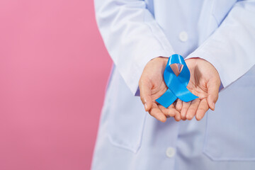 Prostate cancer awareness. Close up medical doctor holding ribbon over pink background isolated....