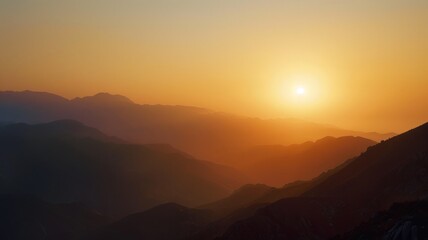 Fototapeta premium Serene mountain silhouette against the sunset sky - This image captures the tranquil beauty of layered mountain silhouettes basking in the orange glow of a setting sun