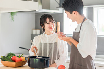 料理を作って味見をする夫婦・カップル・男女（キッチン）

