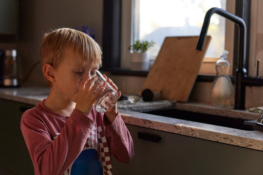 Little boy drinking water in the kithchen 