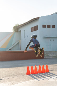 Child Jumping Over Obstacles In A Roller Skating Class Outdoors.