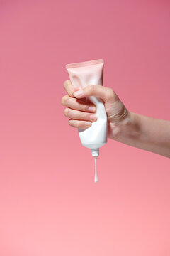 Female hand squeezes cream or gel from tube