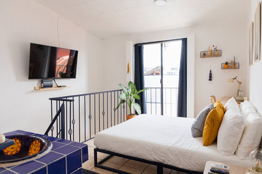 Bed with pillows and white sheets with a tv in a bedroom