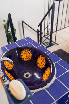 Sink of a blue bathroom with tiles and draws of suns
