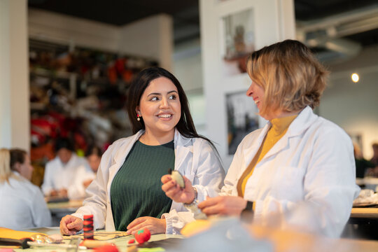 Cheerful women working at table in leather recycling lab