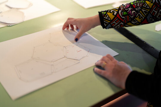 Unrecognizable woman hands showing drawing on table and explaining