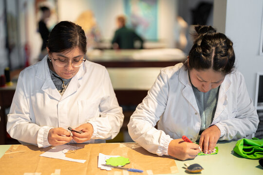 Focused women working on recycled leather fashion products in lab