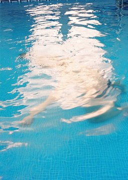 Film photography of anonimous person swimming underwater in pool