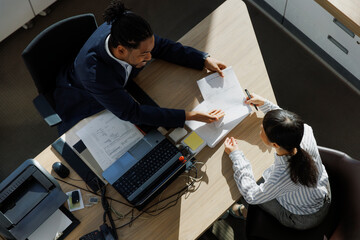 Smiling businessman discussing reports with colleague at office desk