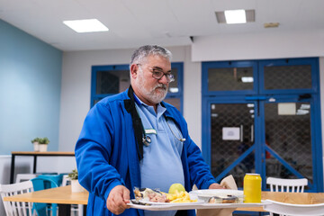 doctor with stethoscope holding a tray of food in a hospital