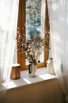 driedd bouquet on window sill with lace curtains. 