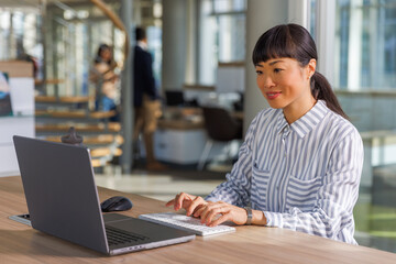 Smiling confident business executive working on laptop at office desk