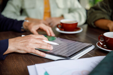 Cropped image of business team analyzing reports on digital tablet