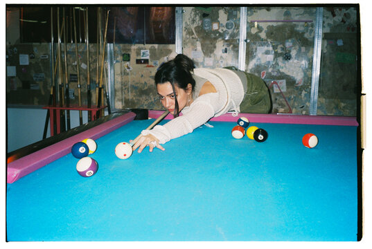 young woman plays billiard