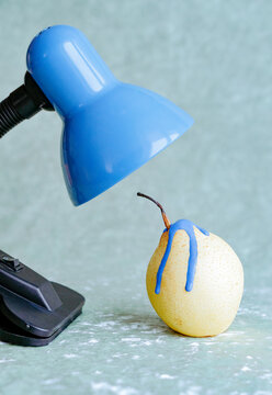 Conceptual still life with a lamp and a pear.