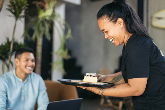 Close-up of a waitress serving coffee and cake in a cafe