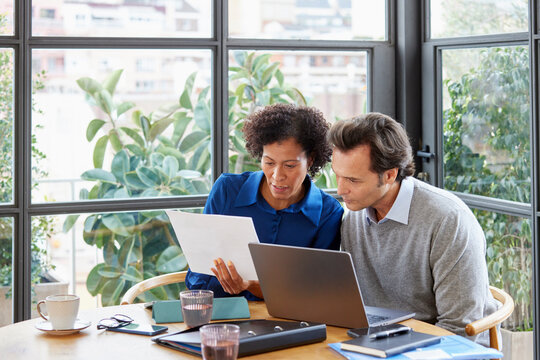 Focused diverse colleagues reading document in office