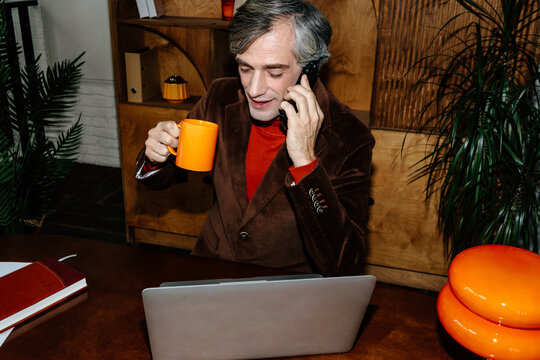 Business phone conversation with coffee in office, direct flash