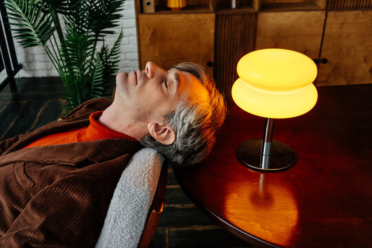 Businessman taking moment of repose near table with retro lamp