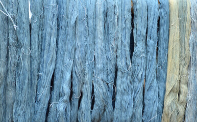 Skeins of hand spun silk thread hanging to dry after being dyed. The threads will be woven into...