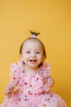 happy baby in dress on yellow backdrop