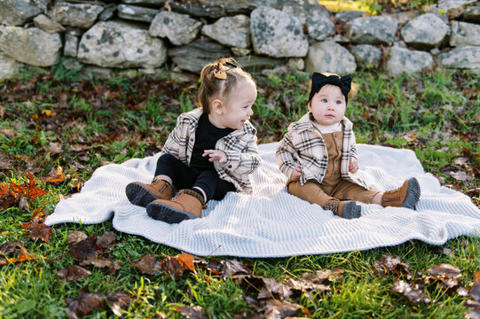 sisters sitting down together on blanket on an autumn day