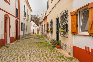 Traditional Portuguese houses line a cobbled street, adorned with wrought-iron window guards. - 777882707