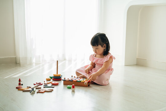 Cute little child playing with xylophone on floor