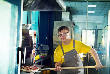 Young guy with Down syndrome making pizza in a pizzeria