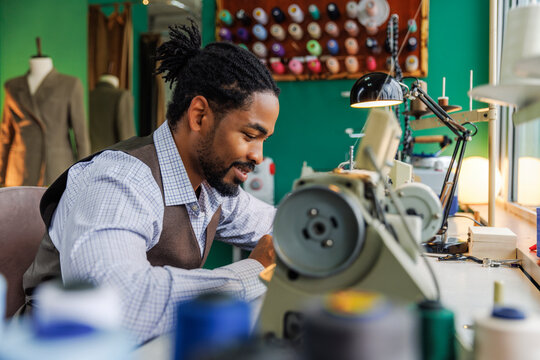 Profile view of skilled tailor working on sewing machine 