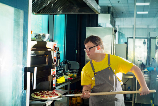 Young guy with Down syndrome making pizza in a pizzeria