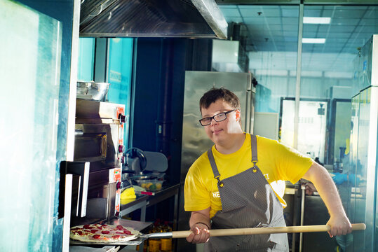 Young guy with Down syndrome making pizza in a pizzeria