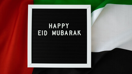 Message text HAPPY EID MUBARAK - happy holidays waving UAE flag on background concept. Greeting card advertisement. Commemoration Day Muslim Ramadan Blessed holy month public holiday. Patriotism