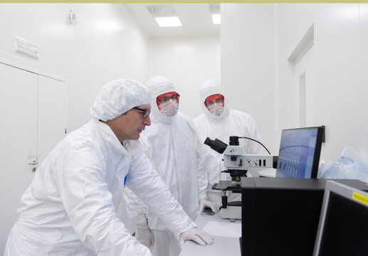 Researchers Working  With Microscope At Clean Room. 