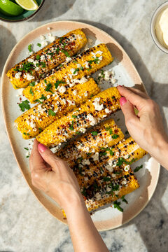 Person eating grilled corn on the cob