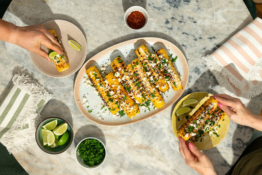Two people eating grilled corn on the cob