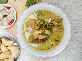 Gulai ayam or chicken curry served in a white bowl. A soupy dish made from chicken cooked with spices and coconut milk. Indonesian traditional cuisine. Top view.