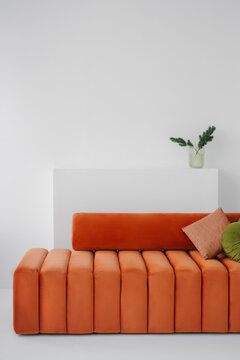 Comfortable orange armless sofa with round back placed at home