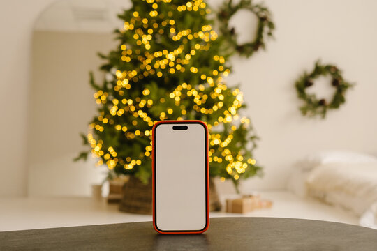 Smartphone with blank screen standing on table in room