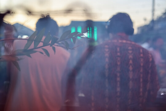 Two anonymous DJs playing at tropical party outdoors and fog blur